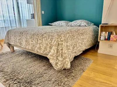 a bed with a blanket and pillows in a bedroom at Studio Cosy Pradignac in Cannes