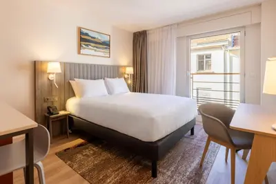 a hotel room with a large bed and a window at Staybridge Suites - Cannes Centre by IHG in Cannes