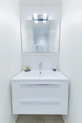 a white bathroom with a sink and a mirror at Alceste Apartment - Cannes Banane in Cannes