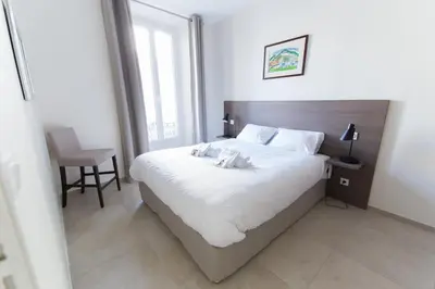a bedroom with a large white bed and a chair at Alceste Apartment - Cannes Banane in Cannes