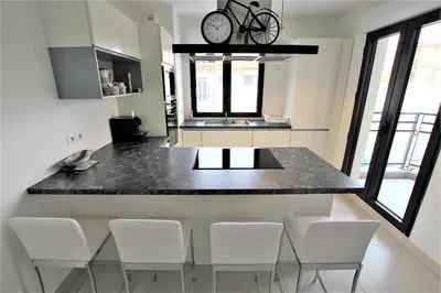 a kitchen with a counter with white chairs around it at VENDÔME APARTMENT in Cannes