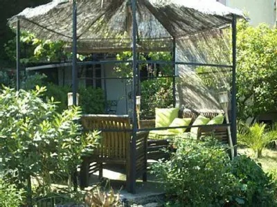 a gazebo with two benches in a garden at Bed & Breakfast Chambres d'hôtes COTTAGE BELLEVUE in Cannes