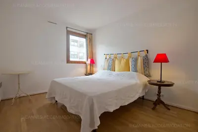 a white bedroom with a bed and a window at Alessandra in Cannes
