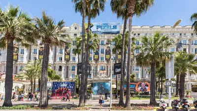a large building with palm trees in front of it at Antares POP in Cannes