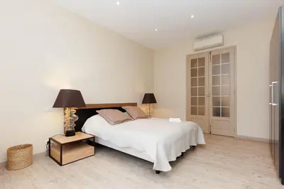 a white bedroom with a bed and a lamp at Carrousel 4 in Cannes