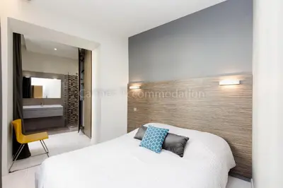 a bedroom with a white bed and a yellow chair at Clic 20 in Cannes