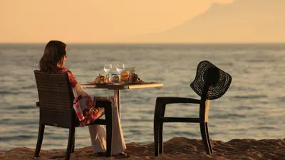 a woman sitting at a table on the beach at Gray 2A2 in Cannes