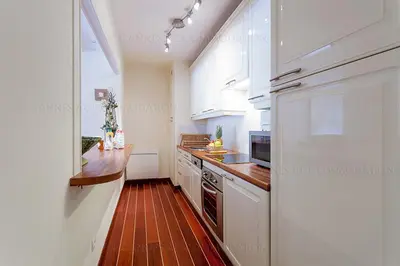 a kitchen with white cabinets and a wooden floor at Gray 2A2 in Cannes