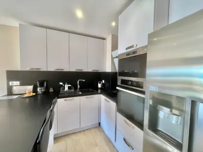 a kitchen with white cabinets and black appliances at Acanthes by Welcome to Cannes in Cannes