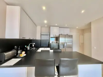 a kitchen with a large black counter with two chairs at Acanthes by Welcome to Cannes in Cannes