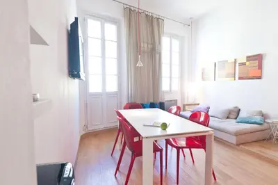 a living room with a white table and red chairs at Festival Apartment in Cannes