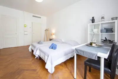 a white bedroom with a bed and a table at Cosy apartment 27 m2 in rue d'Antibes and Croisette in Cannes