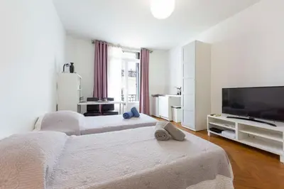 a white bedroom with a bed and a flat screen tv at Cosy apartment 27 m2 in rue d'Antibes and Croisette in Cannes
