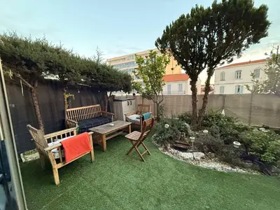 a backyard with two benches and a table and a tree at 13 Rue Edith Cavell in Cannes
