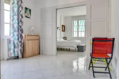 a white room with a bed and a red chair at IMMOGROOM - Sea View - Balcony - 5 min from the beach - AC - Wifi in Cannes