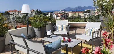 a balcony with chairs and tables on a roof at Sea view Penthouse with terrace in Cannes