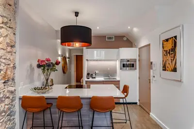 a kitchen with a white table and orange chairs at Luxury Family 2BR - Prime Location, Walk to Beach & Shopping, Sunny Balcony - By Totolulu Cannes Hoche in Cannes