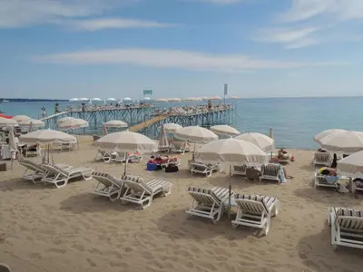 a beach with chairs and umbrellas and a pier at Luxury Family 2BR - Prime Location, Walk to Beach & Shopping, Sunny Balcony - By Totolulu Cannes Hoche in Cannes