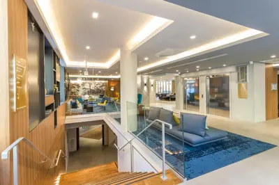 a lobby with a staircase with blue chairs at Nemea Appart Hotel Cannes Palais in Cannes