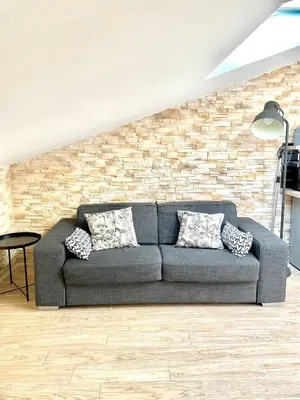 a couch in a living room with a brick wall at Safari apartment in heart of Cannes and beaches in Cannes