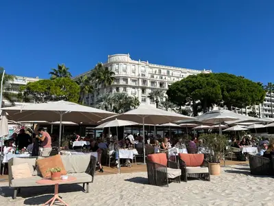 a group of tables and chairs with umbrellas in front of a building at Croisette Palais Miramar - sea view in Cannes