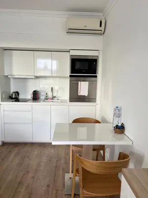 a kitchen with white cabinets and a table and chairs at Croisette Palais Miramar - sea view in Cannes