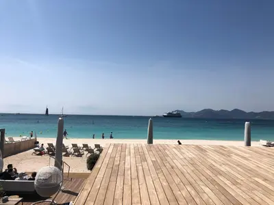 a beach with people sitting on the sand and the ocean at Croisette Palais Miramar - sea view in Cannes