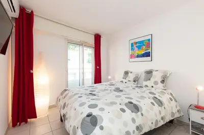 a bedroom with a bed and a window with red curtains at Villa AD’ALTA in Cannes