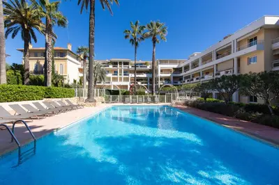 a swimming pool in front of a building with palm trees at Villa AD’ALTA in Cannes