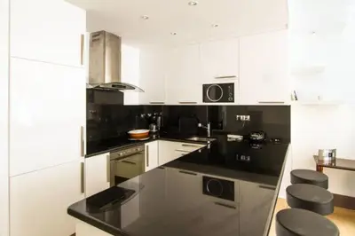 a kitchen with black counter tops and white cabinets at Croisette View Lux Flat Cannes in Cannes