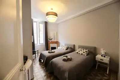 a bedroom with two beds and a light on the wall at 70m2 Apartment - La Roseraie in Cannes