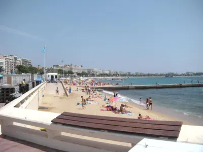 a group of people on a beach near a pier at Marylin 2 pièces 3 étoiles, plein coeur de Cannes, 5mn Palais et plages in Cannes