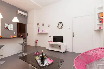 a white living room with a table and a tv at Marylin 2 pièces 3 étoiles, plein coeur de Cannes, 5mn Palais et plages in Cannes