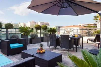a patio with tables and chairs and an umbrella at Nehô Suites Cannes Croisette in Cannes
