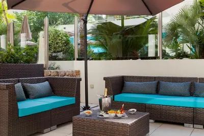 a patio with two wicker chairs and an umbrella at Nehô Suites Cannes Croisette in Cannes