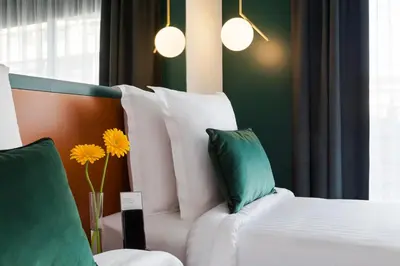 a bedroom with a white bed with green and yellow pillows at Nehô Suites Cannes Croisette in Cannes