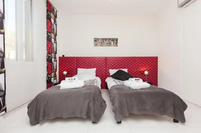 a bedroom with two beds and a red headboard at Manhattan 2 pièces 3 étoiles lumineux plein centre à 5mn des plages et palais in Cannes