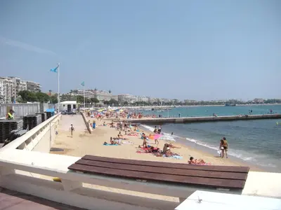 a beach with people on the sand and the water at Manhattan 2 pièces 3 étoiles lumineux plein centre à 5mn des plages et palais in Cannes