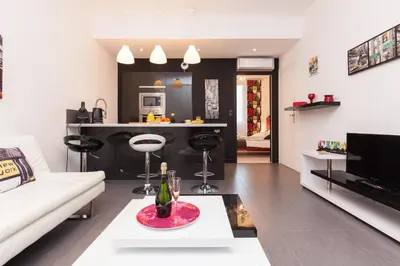 a living room with a white couch and a kitchen at Manhattan 2 pièces 3 étoiles lumineux plein centre à 5mn des plages et palais in Cannes