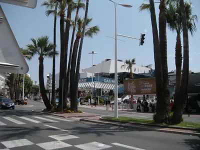 an empty street with palm trees and a building at New York 2 pièces 3 étoiles calme plein centre de cannes, 5mn des plages et Palais in Cannes
