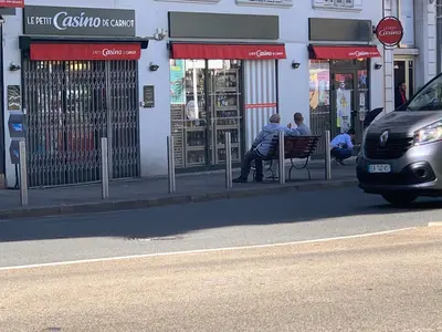 two people sitting on a bench in front of a store at New York 2 pièces 3 étoiles calme plein centre de cannes, 5mn des plages et Palais in Cannes