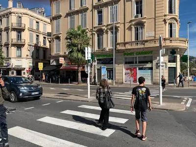 two people waiting to cross the street at a crosswalk at Charlie Chaplin 2 pièces 3 étoiles calme plein centre de Cannes, 5mn des plages et Palais in Cannes