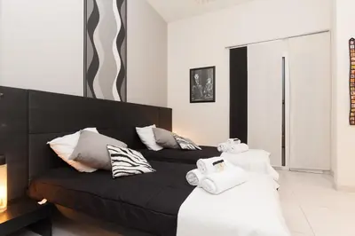 a bedroom with a black bed and white pillows at Charlie Chaplin 2 pièces 3 étoiles calme plein centre de Cannes, 5mn des plages et Palais in Cannes
