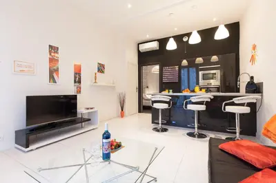 a living room with a large television and a kitchen at Voyage 2 pièces 3 étoiles calme plein centre à 5mn des plages et du Palais in Cannes