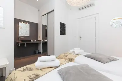 two beds in a white room with a mirror at Voyage 2 pièces 3 étoiles calme plein centre à 5mn des plages et du Palais in Cannes