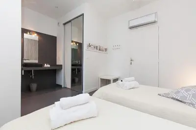 a white bedroom with two beds and a mirror at Nature 2 pièces 3 étoiles calme plein centre cannes 5 mn des plages et Palais in Cannes