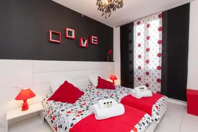 a bedroom with a red and white bed with red pillows at 7e Art 2 pièces 3 étoiles calme plein centre Cannes 5mn plages et Palais in Cannes