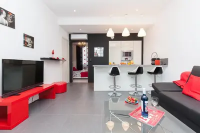 a living room with a black and red couch and a kitchen at 7e Art 2 pièces 3 étoiles calme plein centre Cannes 5mn plages et Palais in Cannes