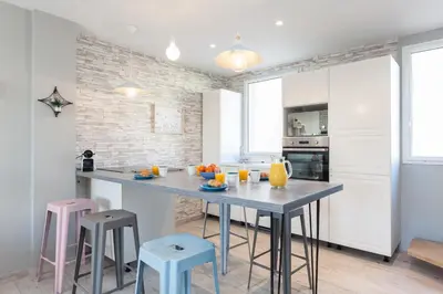 a kitchen with a table and stools in a room at Cocooning 3 pièces duplex 3 étoiles calme centre ville à 5mn plages et Palais in Cannes
