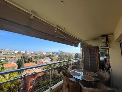 a balcony with tables and chairs and a view of a city at Les Roses by Welcome to Cannes in Cannes
